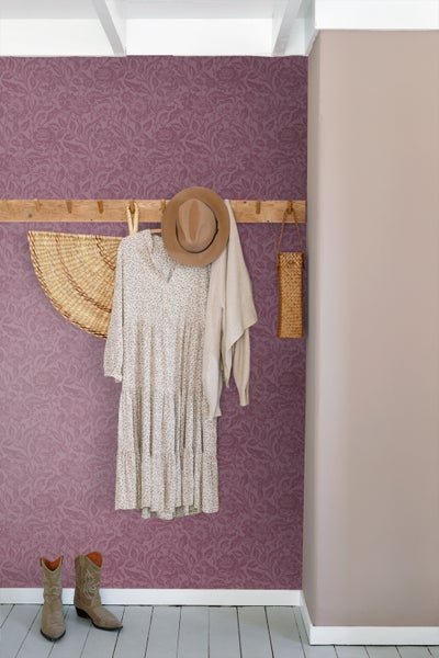 Raumszene mit floral gemusterter Tapete, Garderobe mit Kleidung und Stiefeln