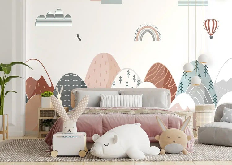 Kinderzimmer mit einer Vliestapete, die eine stilisierte Berglandschaft mit Regenbogen, Heißluftballon und Bäumen zeigt.