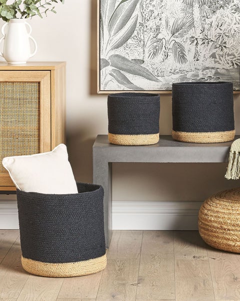 Dreiteiliges Set aus schwarz-naturfarben geflochtenen Aufbewahrungskörben aus Baumwolle und Jute in einem hellen Wohnraum.