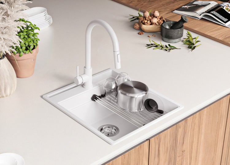 Spüle mit Abtropffläche, Wasserhahn und Geschirr auf einer Küchentheke.