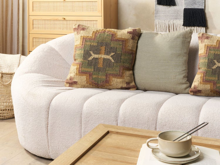 Wohnzimmer mit Sofa, Kissen, Tisch und Dekorationen.