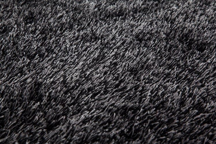 Detailansicht eines anthrazitfarbenen Hochflor-Teppichs mit dichten, weichen Fasern.
