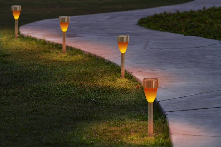 Szene mit mehreren Solarleuchten in einem Garten entlang eines Weges.