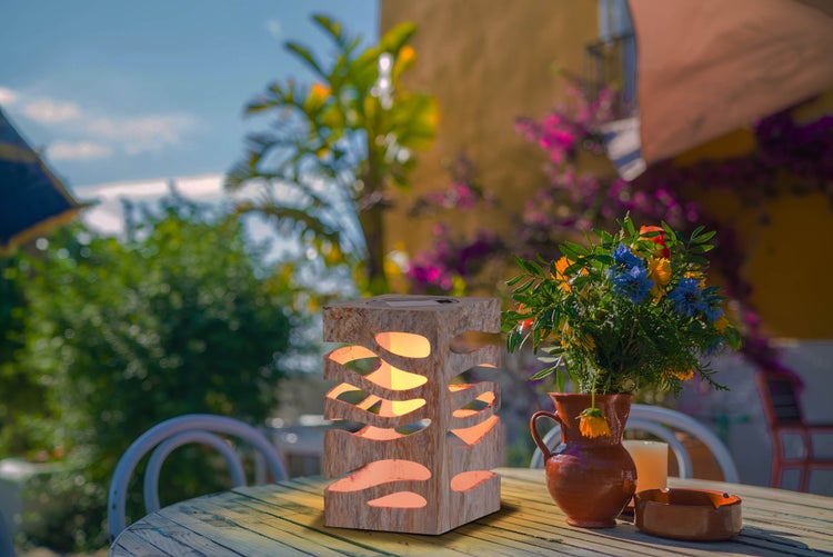 Szene im Garten mit einem Holztisch, Stühlen und einer dekorativen Solarleuchte