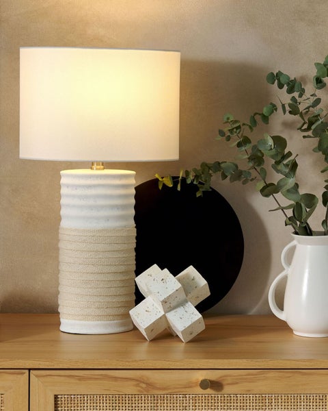 Dekorative Szene mit Tischleuchte, geometrischer Skulptur und Vase auf einem Holzschrank