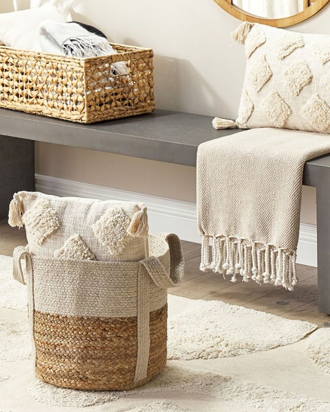 Dekorative Szene mit Körben, Kissen und Textilien auf einem grauen Betontisch