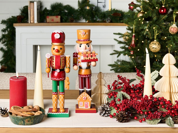 Weihnachtliche Tischdekoration mit Nussknackern, Kerzen und Tannengrün im Hintergrund