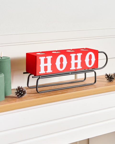 Dekorativer Teelichthalter in Schlittenform mit der Aufschrift 'HO HO HO' als festliche Tischdekoration