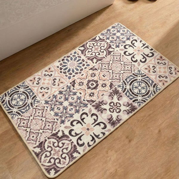 Rechteckiger Badteppich mit Patchwork-Muster aus verschiedenen Ornamenten auf einem Holzboden neben einer Badewanne.