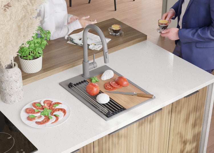 Küchenszene mit Spüle, Armatur, Schneidebrett mit Tomaten, Mozzarella und Basilikum