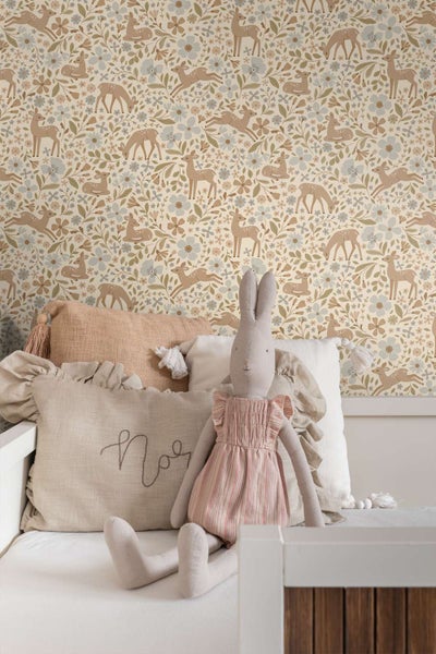 Kindertapete mit Waldmotiven wie Rehen und Blumen in einem Kinderzimmer mit dekorativen Kissen und Stofftier.