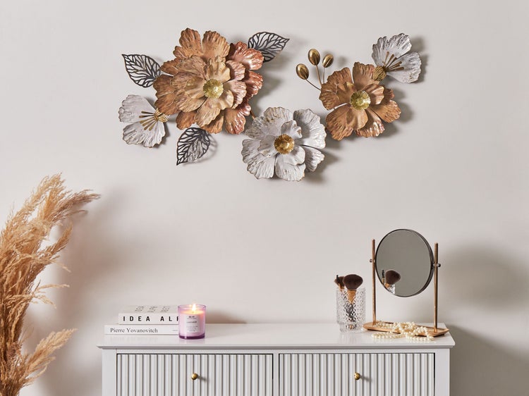 Dekorative Metallblumenwandkunst über weißem Schrank mit Spiegel, Kerze und Dekoration