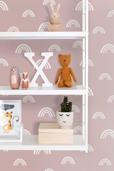 Regal mit Dekorationselementen wie Holzspielzeug, Stofftier und Topfpflanze vor einer Wand mit Regenbogenmuster