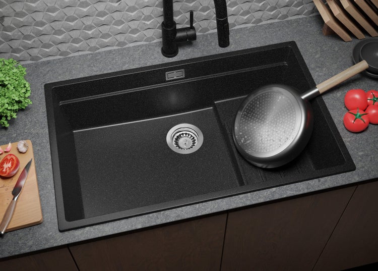 Schwarzes Spülbecken aus Granit mit Abtropffläche und Armatur auf einer Arbeitsplatte