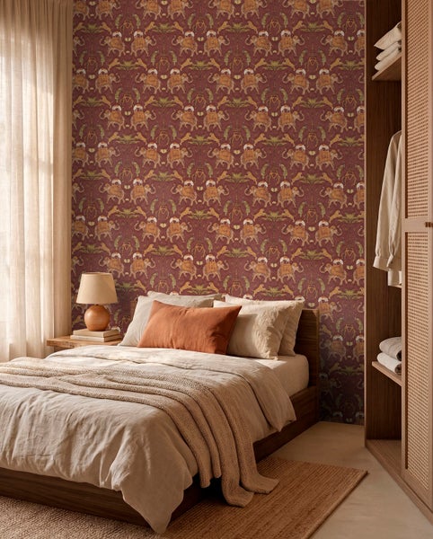 Schlafzimmer mit gemusterter Tapete mit Elefanten- und Leopardenmotiven, Bett mit hellen Textilien und Holzmöbeln.