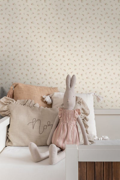Tapete mit feinem Blumenmuster in einem gemütlichen Kinderzimmer mit dekorativen Kissen und einem Stoffhasen.