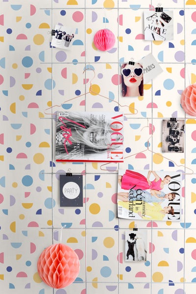 Tapete mit geometrischem Muster aus bunten Kreisen und Halbkreisen, dekoriert mit einem Metallgitter, Zeitschriften und Fotos.
