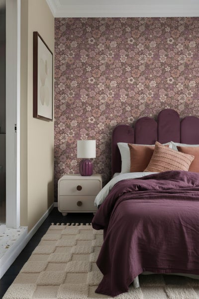Schlafzimmer mit Blumenmustertapete, Bett, Nachttisch, Lampe und Teppich