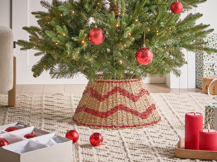 Dekorierter Weihnachtsbaum mit Christbaumkugeln und einem geflochtenen Baumständer