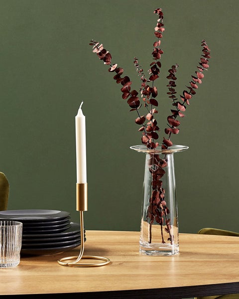 Dekoration mit Kerze, Kerzenständer, Vase und Pflanzen auf einem Tisch