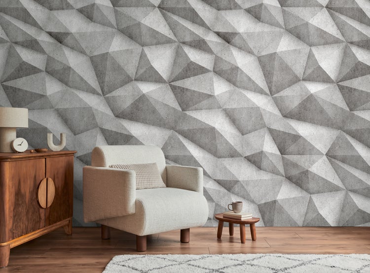 Modernes Wohnzimmer mit hellem Sessel, Holzkommode und einer 3D-Fototapete in Beton-Optik mit geometrischem Muster.