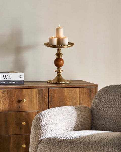 Dekorative Kerzen auf einem Kerzenständer aus Holz und Metall auf einer Kommode
