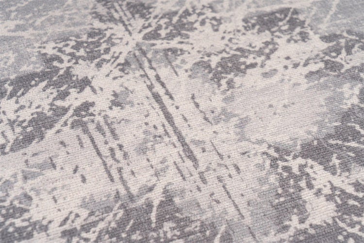 Detailaufnahme eines grauen Teppichs mit abstraktem, verwaschenem Muster im Vintage-Stil.