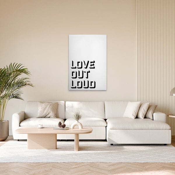 Wohnzimmer mit Sofa, Tisch und gerahmtem Wandbild mit dem Text 'Love Out Loud'.