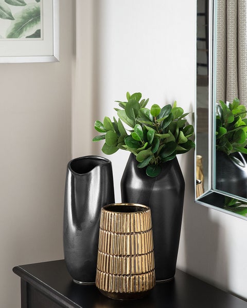 Dekorative Anordnung mit zwei schwarzen Vasen und einer goldenen Vase auf einem Tisch