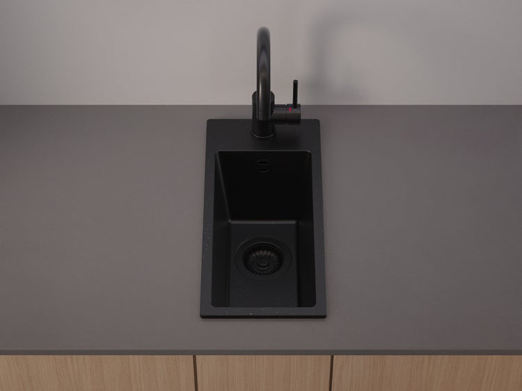 Moderne schwarze Küchenspüle mit schwarzer Armatur, eingebaut in eine graue Arbeitsplatte über Holzunterschränken.