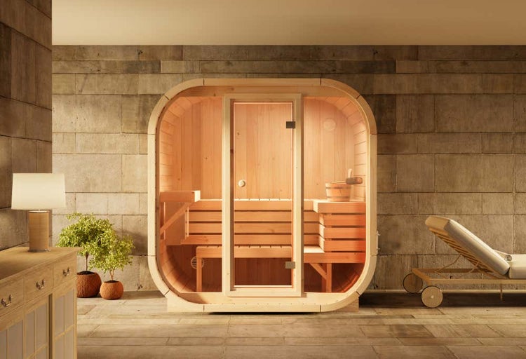 Moderne Fasssauna aus Holz mit Glastür, Innenbänken und Saunaeimer in einem Wellnessbereich.