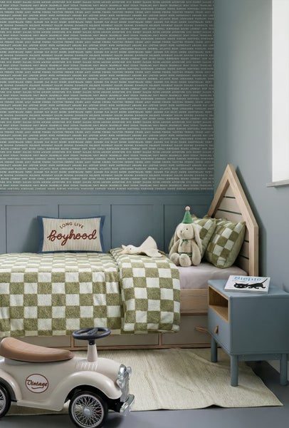 Ein modern eingerichtetes Kinderzimmer mit einem Hausbett aus Holz, karierter Bettwäsche, einem blauen Nachtschrank und einem beigen Rutschauto.