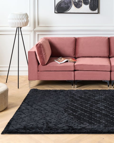 Wohnzimmer mit Sofa, Stehlampe und schwarzem Teppich