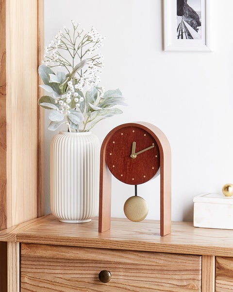 Pendeluhr aus Holz mit Messingpendel auf einer Kommode