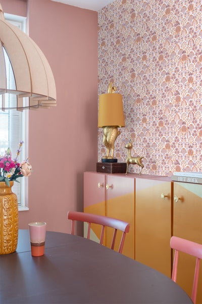 Wohnzimmer mit gemusterter Tapete, grüner Couch und Beistelltisch.