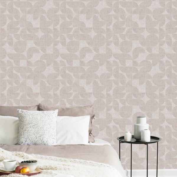 Modernes Schlafzimmer mit geometrischer Tapete, Bett mit Kissen und Strickdecke sowie Beistelltisch mit Vasen in heller, geordneter Atmosphäre.