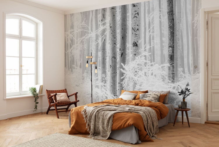 Schlafzimmer mit Fototapete mit Winterwald-Motiv, Bett und Holzmöbeln für eine helle und freundliche Atmosphäre