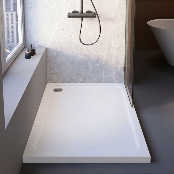 Weiße rechteckige Duschwanne in modernem Badezimmer mit Marmorwand, Glaswand und dunkler Armatur.