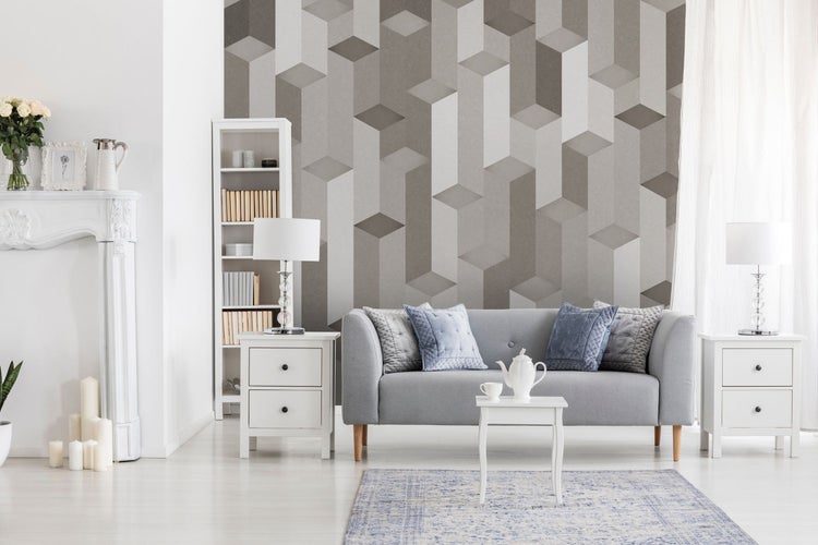 Wohnzimmer mit grauem Sofa, geometrischer Tapete und weißen Möbeln