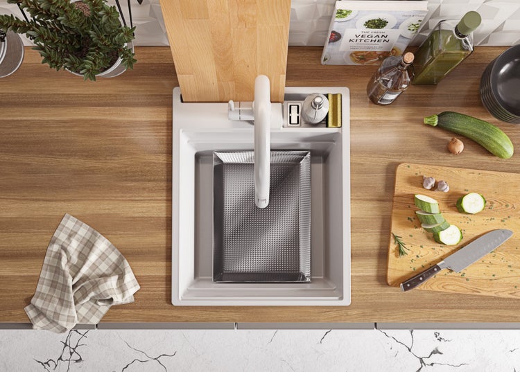 Küchenszene mit Spüle, Armatur, Schneidebrett und Lebensmitteln auf einer hölzernen Arbeitsplatte