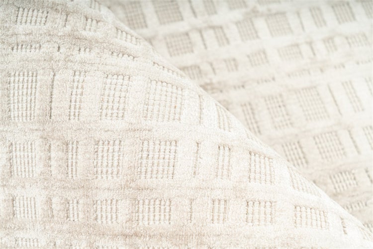 Beigefarbener strukturierter Teppich mit geometrischem Karomuster und Hoch-Tief-Struktur.