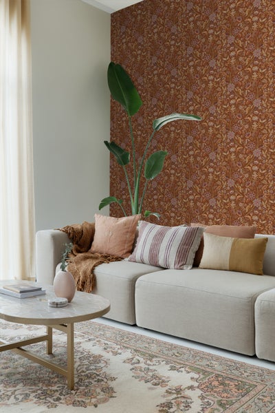 Wohnzimmer mit blumiger Tapete, Sessel, Schrank und Holztisch