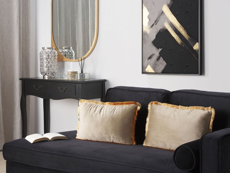 Wohnzimmer mit schwarzem Sofa, Kissen mit Fransen, Konsole und Dekoration