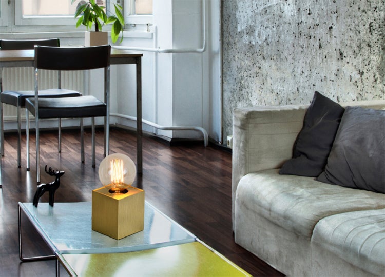 Innenaufnahme eines Wohnbereichs mit Tischlampe, Sofa und Esstisch