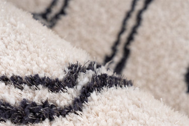Detailaufnahme eines weichen Hochflor-Teppichs mit dunklem Linienmuster.