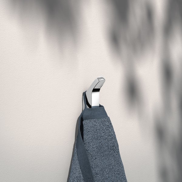 Ein glänzender Handtuchhaken aus Metall ist an einer Wand montiert, an dem ein strukturiertes Handtuch mit Aufhängeschlaufe hängt.