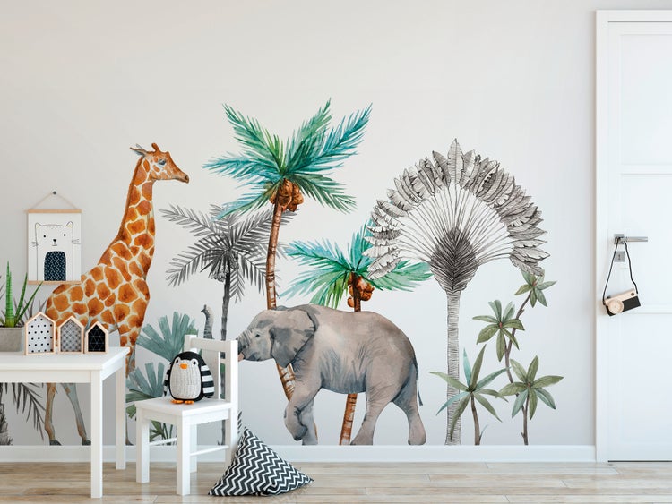 Wandtapete im Safari-Design mit einer Giraffe, einem Elefanten und Palmen in einem hellen Kinderzimmer mit weißen Möbeln.