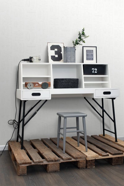 Schreibtisch mit Regalfächern und einem grauen Hocker auf Holzpaletten