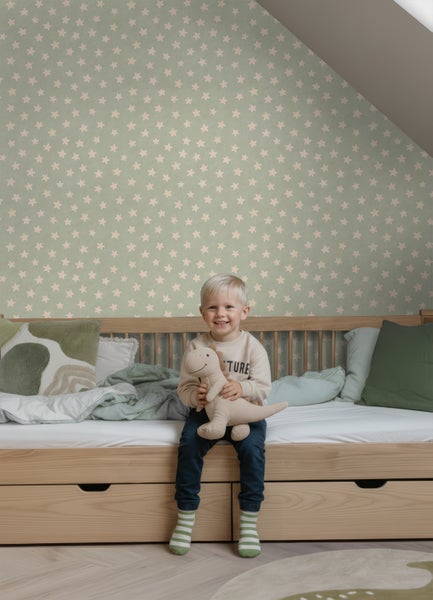 Vliestapete mit Sternenmuster im Kinderzimmer an einer Wand mit Dachschräge hinter einem Holzbett.