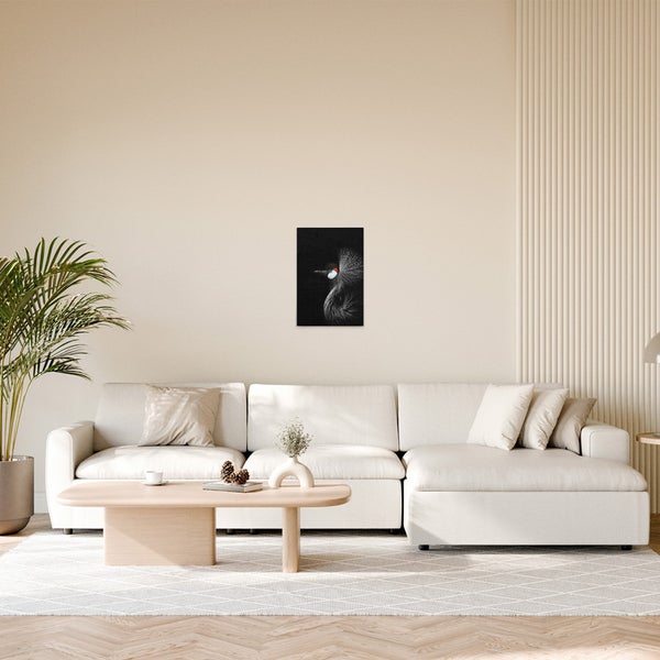 Wohnzimmer mit Sofa, Tisch und einem gerahmten Bild einer Kronenkranich-Illustration an der Wand.